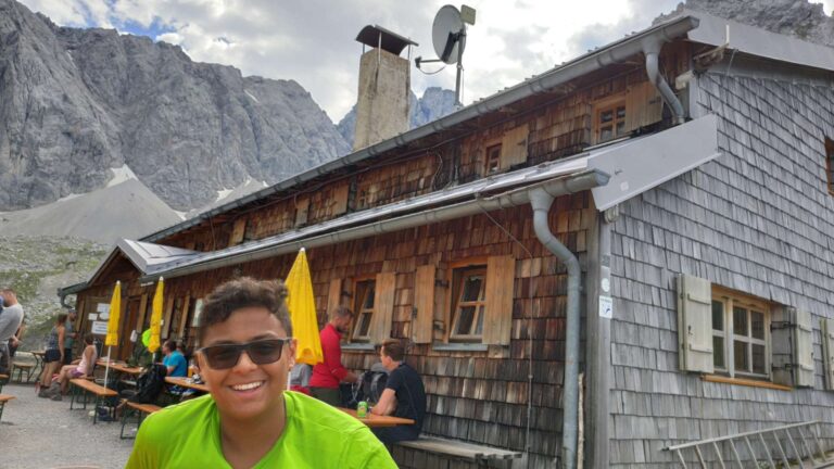 Lächelnder Junge vor einer Berghütte am Drachensee